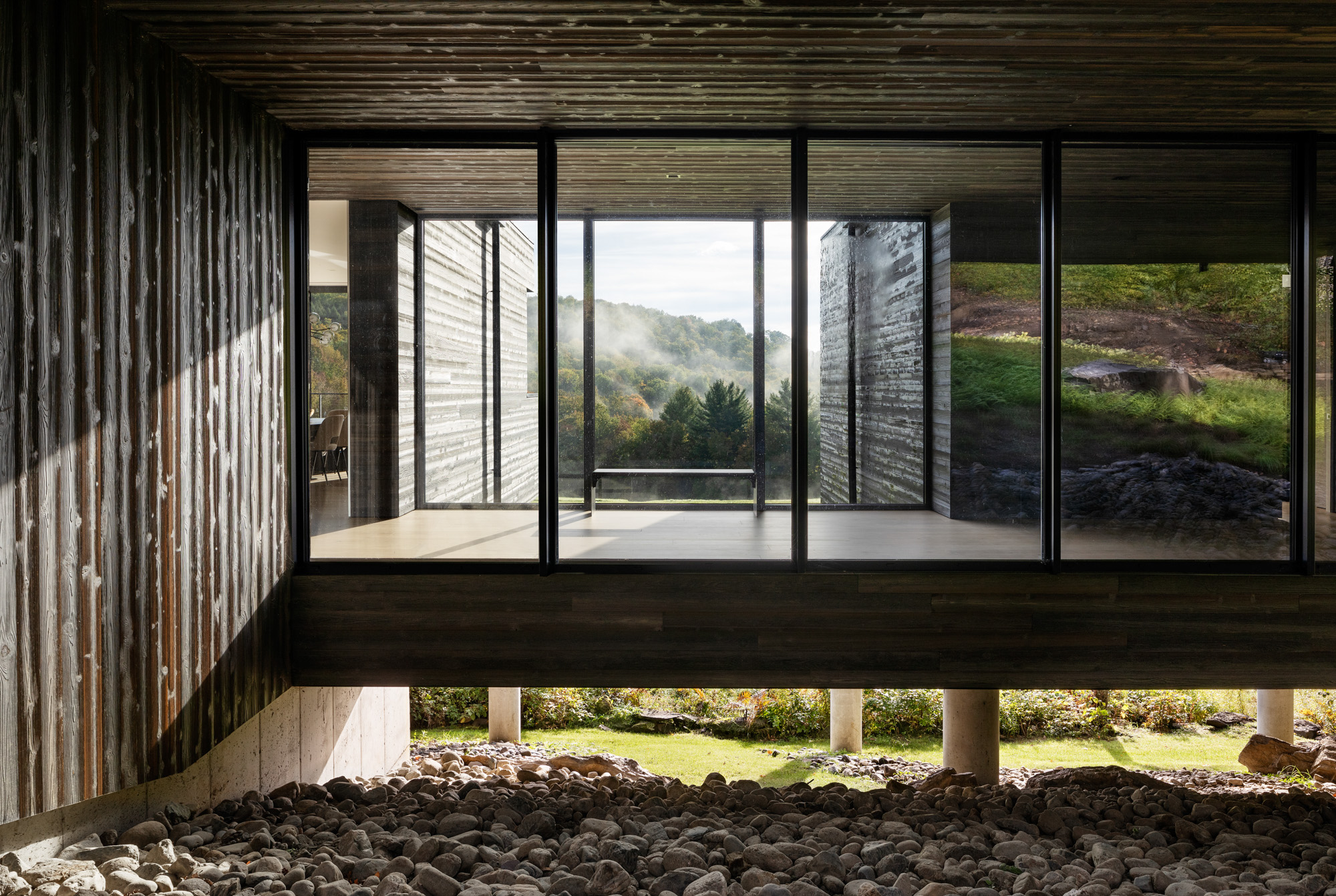 Large format fixed glazing with black aluminium frame, forest view through floor-to-ceiling windows